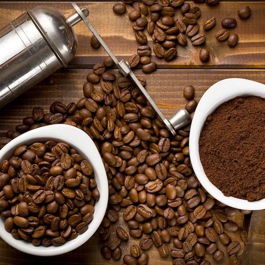 A grinder, whole beans and fresh grounds on the bench
